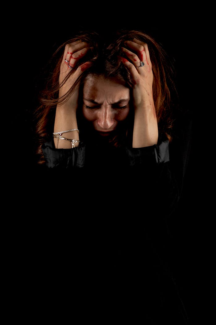 Dementia Support Woman holding head in distress against a dark background, symbolizing emotional struggle.