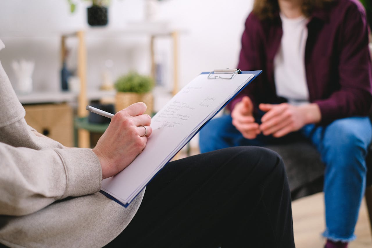 Empowering Community Healthcare and Education | South Africa Empowering community healthcare and education. Close-up of a therapist writing notes on a clipboard while conversing with a patient.